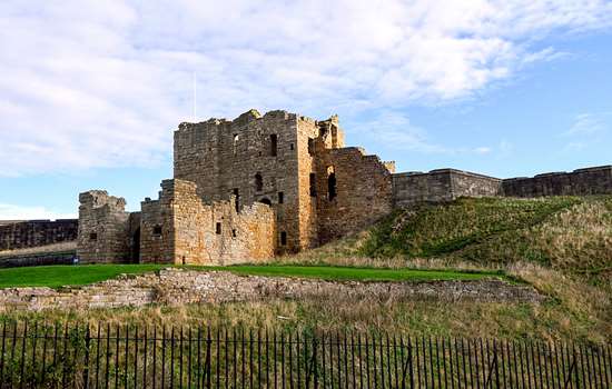 A low angle view of Tynemouth Priory on top of a hill.