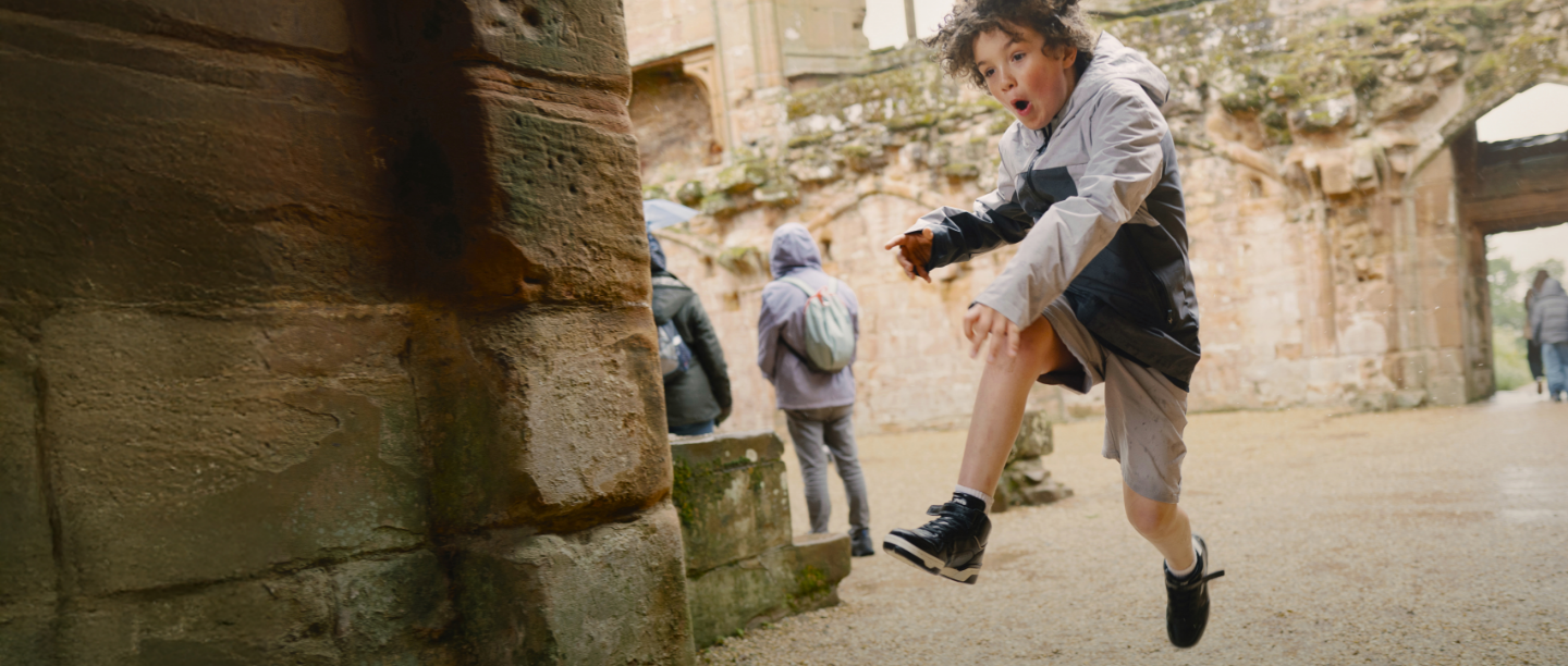 Photo of a child jumping in the rain at Kenilworth Castle and Elizabethan Garden in Warwickshire